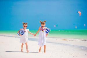 Entzückende kleine Mädchen mit Handtüchern am tropischen Strand foto
