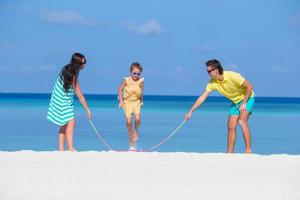 glückliche Familie, die zusammen am weißen Strand spielt foto