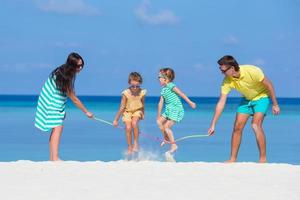 glückliche Familie, die zusammen am weißen Strand spielt foto