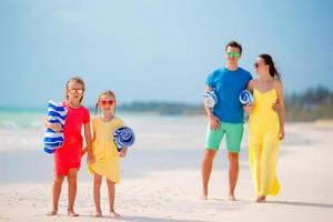 junge vierköpfige Familie mit Handtüchern im Urlaub foto