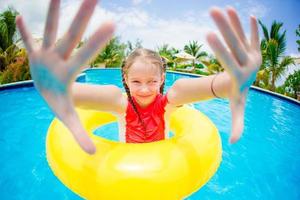 Porträt eines glücklichen Kindes mit aufblasbarem Gummikreis, das sich im Schwimmbad amüsiert foto
