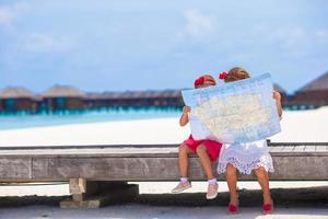 entzückende kleine Mädchen mit Karte der Insel am Strand foto