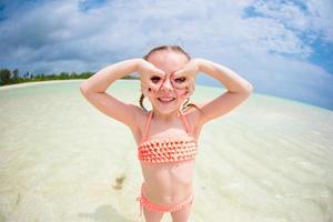 entzückendes kleines Mädchen, das sich während der Sommerferien wie ein Superheld am Strand amüsiert foto