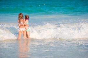 Kinder, die sich während der Sommerferien am tropischen Strand amüsieren, spielen zusammen im seichten Wasser foto