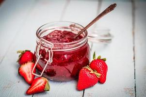 Erdbeermarmelade in einem Glas auf hölzernem Hintergrund foto