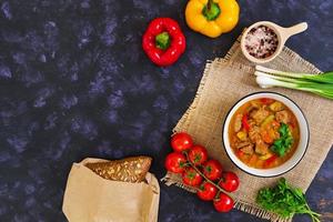 Eintopf mit Fleisch und Gemüse in Tomatensauce auf dunklem Hintergrund foto
