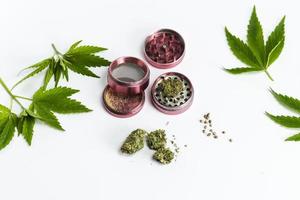 Nahaufnahme von medizinischen Marihuana-Knospen, Hanfsamen, Blättern und Mühle auf weißem Hintergrund.