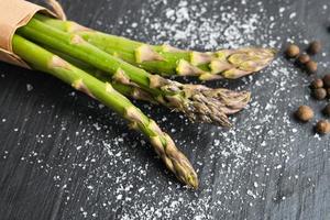 Nahaufnahme von frischem grünem Bio-Spargel mit Salz und Pfeffer. Konzept der gesunden vegetarischen Ernährung, Ernährung und Hausmannskost.