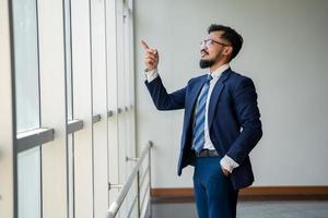 Junger Geschäftsmann, der am Fenster steht foto