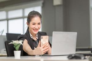 fröhliche Geschäftsfrau mit Telefon im Büro. Aufgeregtes hübsches Mädchen mit Smartphone im Büro, Frau, die in ihrem Heimbüro arbeitet foto