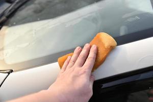 Waschen eines weißen Autos mit einem Schwamm von Hand foto