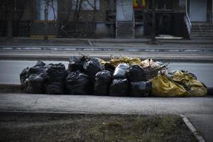 Müllcontainer und Säcke mit Müll auf der Straße foto