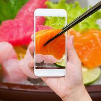 weibliche hand, die foto des sashimi-sushi-sets macht