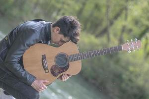 stimmungsvolles Foto eines Jungen, dessen Kopf auf der Gitarre ruht