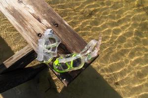 sonnengewaschene bank mit taucherbrille über buchtwasser im sonnenlicht foto