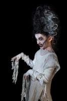 studio shot porträt eines jungen mädchens in kostüm gekleidet wie ein halloween, cosplay der gruseligen braut von frankenstein posieren auf isoliertem schwarzem hintergrund foto
