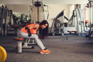 Wunderschöne Brünette, die in einem Fitnessstudio an ihrem Bizeps arbeitet foto