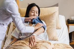 Krankenschwester, die den Blutdruck einer reifen Patientin im Krankenhausbett nimmt. foto