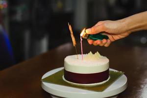 Frau, die zu Hause eine Kerze auf einem Geburtstagskuchen anzündet. foto