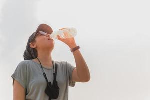 touristische frau, die trinkwasser aus der flasche hydratisiert. foto