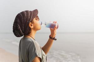 touristische frau, die trinkwasser aus der flasche hydratisiert. foto