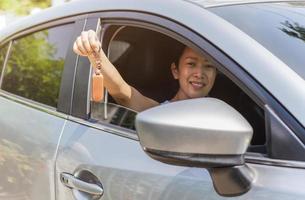 Frau, die einen Autoschlüssel in der Hand hält, während sie in ihrem Auto sitzt. foto