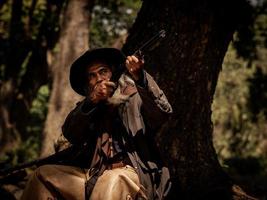 Der ältere Cowboy zielt mit dem Gewehr auf den Angreifer, während die Sicherheitsüberwachung ländliche Farmgebiete durchführt foto