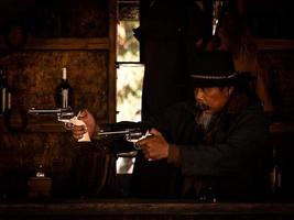 westliche Cowboys kämpfen mit Waffen, um sich in der Taverne zu schützen, auf dem Land, das das Gesetz noch nicht erreicht hat foto