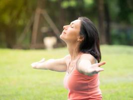 Europäische Frauen sitzen, strecken die Arme, meditieren und entspannen sich in den Morgenstunden beim Yoga in einem Park im Freien foto