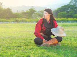 ein wunderschönes Western-Cowgirl, das nach harter Arbeit auf einer Wiese auf einem Bauernhof sitzt foto