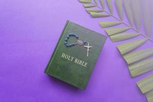 die heilige bibel, kreuz und palmblätter auf violettem hintergrund. Konzept der Karwoche. foto
