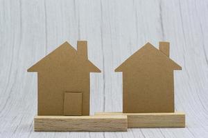 Haus braunes Papiermodell auf weißem Hintergrund aus Holz. Immobilieninvestitionskonzept foto