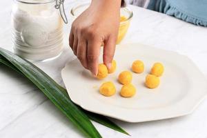 weibliche indonesierin legte biji salak kabocha, gelbe süßkartoffel oder kürbisreiskuchen, kochprozess in der küche, der takjil für buka puasa ramadan frühstückt foto