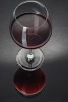 Glas gefüllt mit Wein auf einem schwarzen Tisch foto