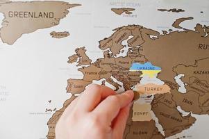 Rubbelreisekarte der Welt. Menschenhand löschen Europa Truthahn mit Münze. foto