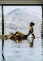 junge Frau, die sich im Winter am Pool des Infinity-Pools entspannt foto