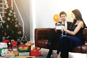 süßes paar liebt lächeln und verbringt romantische weihnachtszeit und feiert silvester auf brauner sofadekoration mit weihnachtsbaum, buntem ballon und geschenkboxen im wohnzimmer zu hause foto