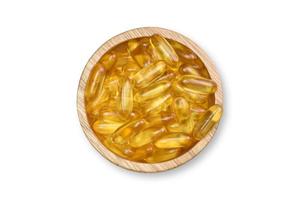 Beschneidungspfad. flache Lage von Ergänzungsfutter. Goldlachsfischölkapseln auf hölzerner Schüssel lokalisiert auf weißem Hintergrund. Omega 3. Vitamin D und E. Ansicht von oben. foto