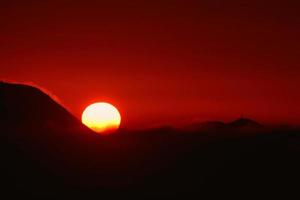 große Sonne in einem feuerroten Sonnenuntergang auf einer Insel foto