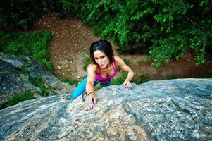 schönes dunkelhaariges Mädchen klettert auf Felsen foto