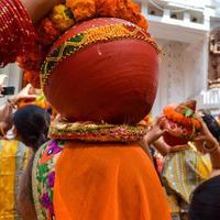 frauen mit kalash auf dem kopf während des jagannath-tempels mangal kalash yatra, indische hindu-anhänger tragen irdene töpfe mit heiligem wasser mit einer kokosnuss darauf foto