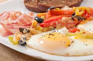 Frühstück - Spiegeleier mit Speck, Tomaten, Oliven und Käsescheiben foto