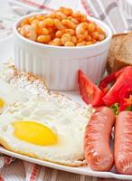 englisches Frühstück - Würstchen, Eier, Bohnen und Salat foto