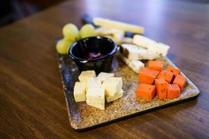 Käse und Trauben mit Sauce auf Wurstbrett foto