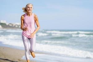 Ältere Sportlerin, die im Sommer am Meer entlang läuft foto