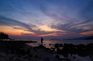 szene des schönen sonnenuntergangs und der silhouette eines mannes am strand foto