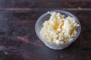 gehackter Knoblauch wird in einen durchsichtigen Plastikbecher auf den Holztisch gelegt. es ist eine Zugabe mit Sukiyaki- oder Shabu-Sauce. foto