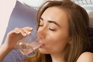 Frau trinkt Wasser morgens zu Hause im Bett, Gesundheitskonzept foto