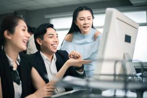 Drei aufgeregte Mitarbeiter lesen gute Nachrichten online auf einem Computer-Desktop im Büro