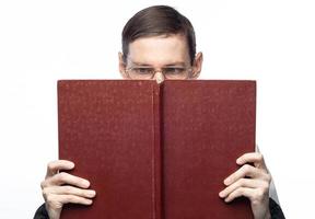 Das Gesicht des Mannes ist von einem großen roten Notizbuch auf einem isolierten Hintergrund bedeckt foto